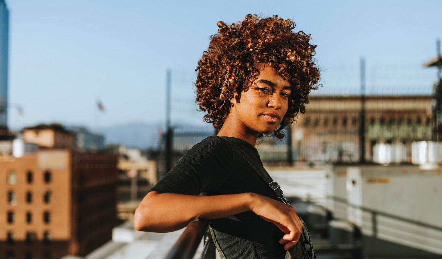 Image d’une jeune personne Noire appuyée contre une balustrade sur fond de paysage urbain sur une page Web de Jeunesse, J’écoute.