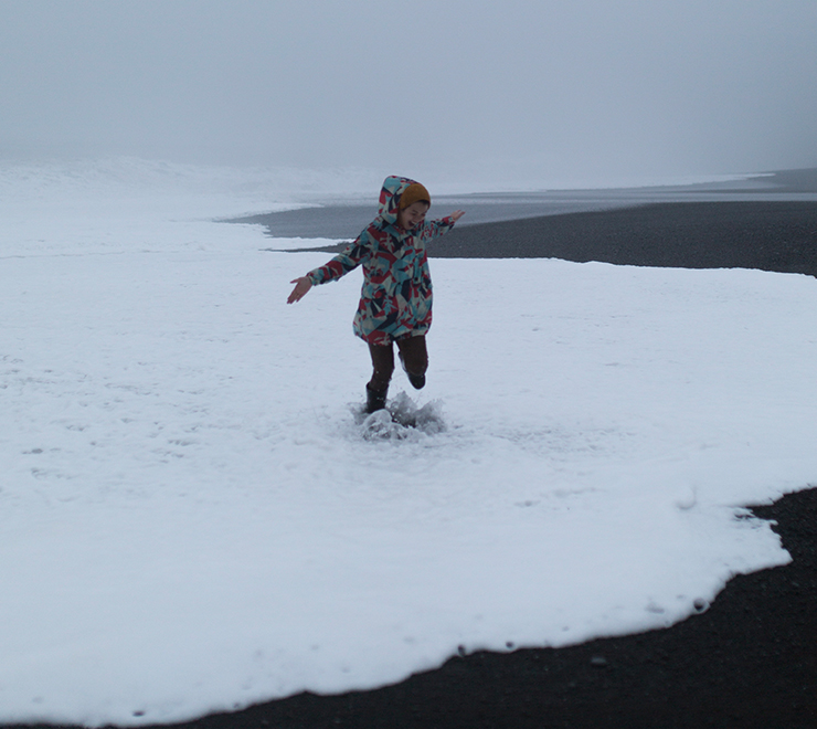 Une jeune personne portant un manteau d'hiver et sautant joyeusement dans la neige