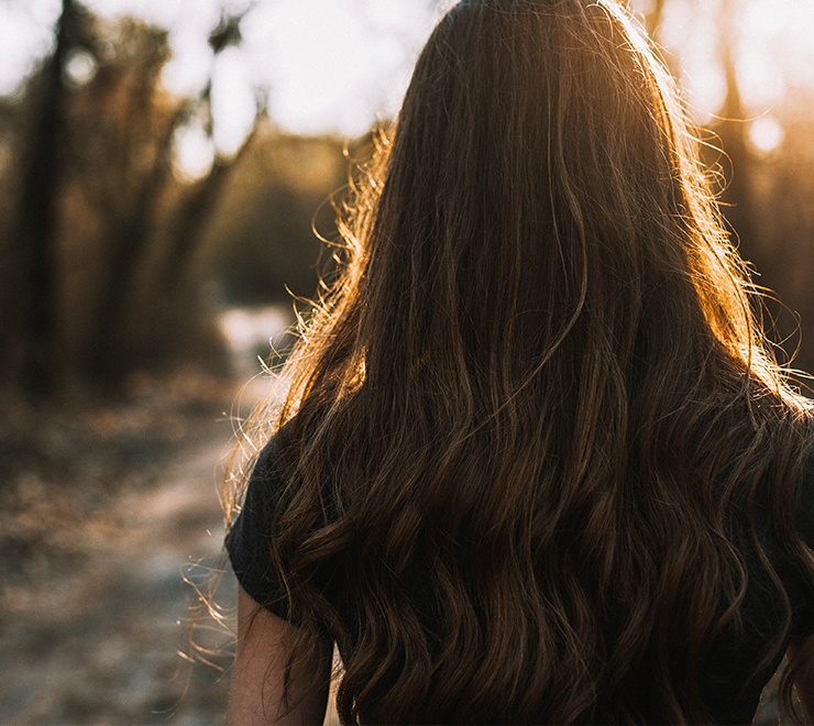 Une jeune personne marchant dans une forêt avec un ruisseau, le dos tourné à la caméra