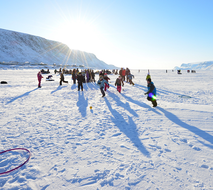 De jeunes personnes jouant dans la neige avec un arrière-plan ensoleillé parmi les montagnes