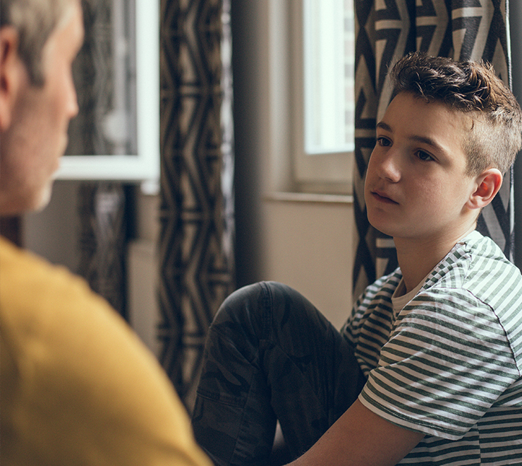 Une jeune personne assise et écoutant un·e adulte bienveillant·e