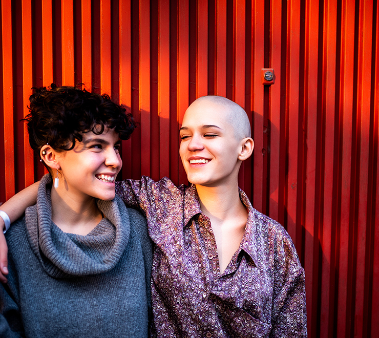 Une jeune personne assise sur des coussins souriant